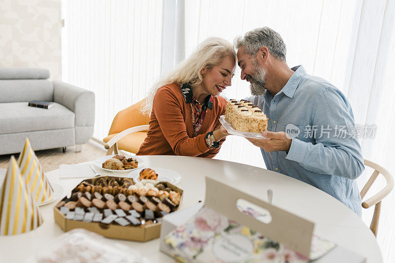 美丽的老年情侣在家里度过一天，吃饼干，享受他们在一起的时光