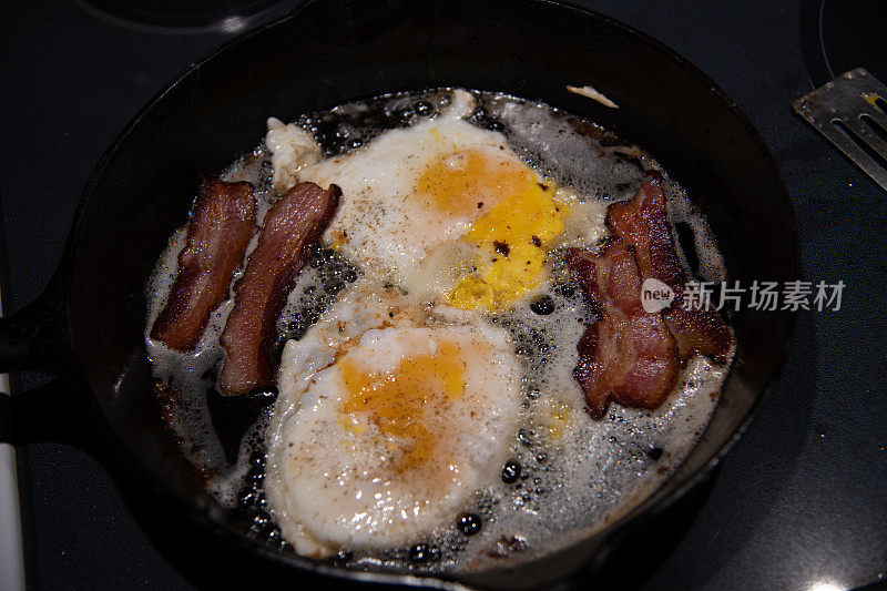 用铁锅煎新鲜的农场饲养的鸡蛋和培根