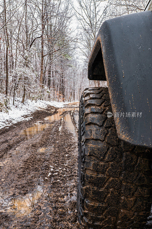 冬季越野4x4探险旅行，近距离，前轮胎视图，在泥泞的田纳西州，山路与小雪。