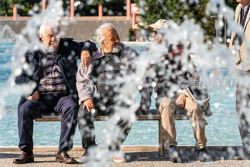 活跃的老朋友在公园度过美好的一天。
坐在喷泉旁边。