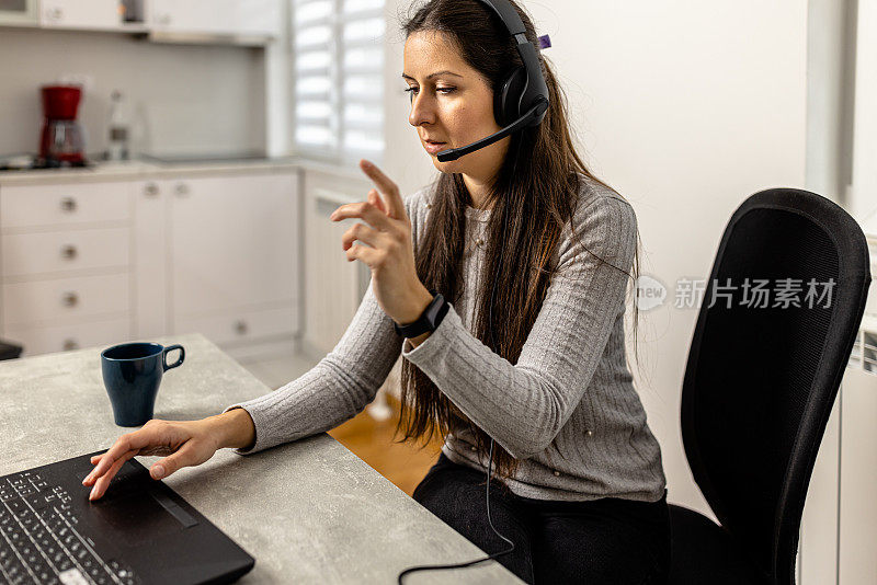一位戴着耳机的呼叫中心女座席正在办公室上网工作。