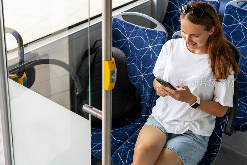城市公共交通生活方式。女乘客在乘坐穿梭巴士时使用她的智能手机。