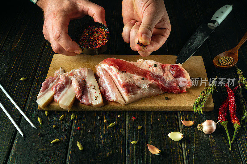 在酒吧厨房里用猪油和调味料准备三明治作为小吃的过程。厨师用刀在砧板上往猪油里加入干香料