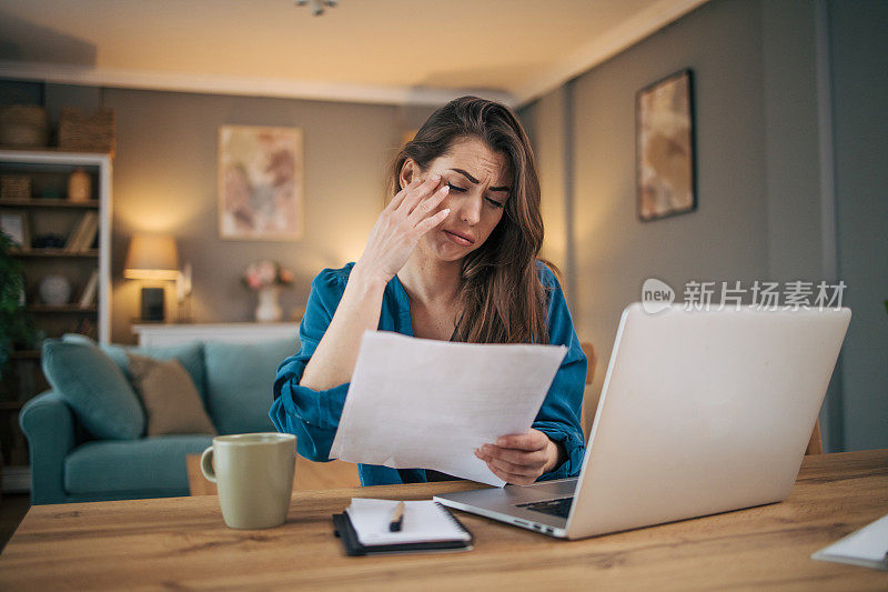 迷人的成年女商人独自坐在家里的办公室里，感觉压力很大