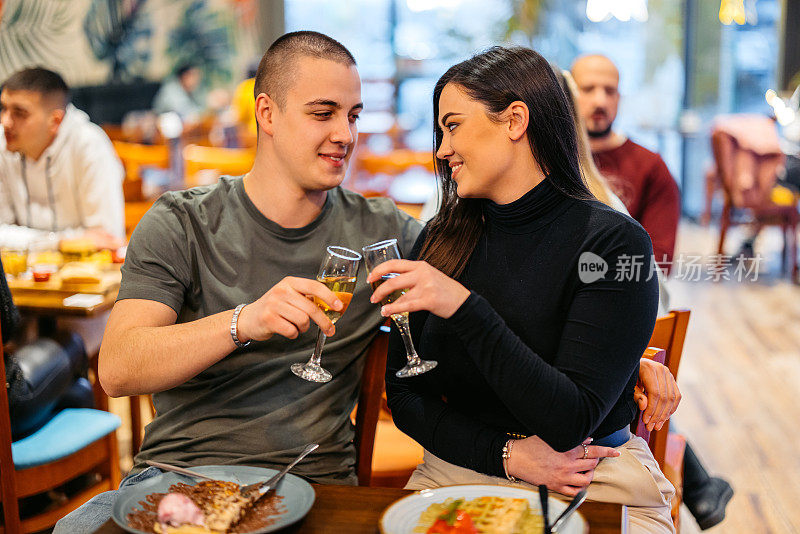 年轻夫妇在酒吧里一边喝着香槟一边吃着比利时华夫饼