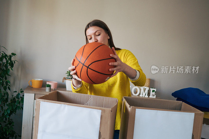 一位年轻女子把一个篮球放进一个纸板捐款箱