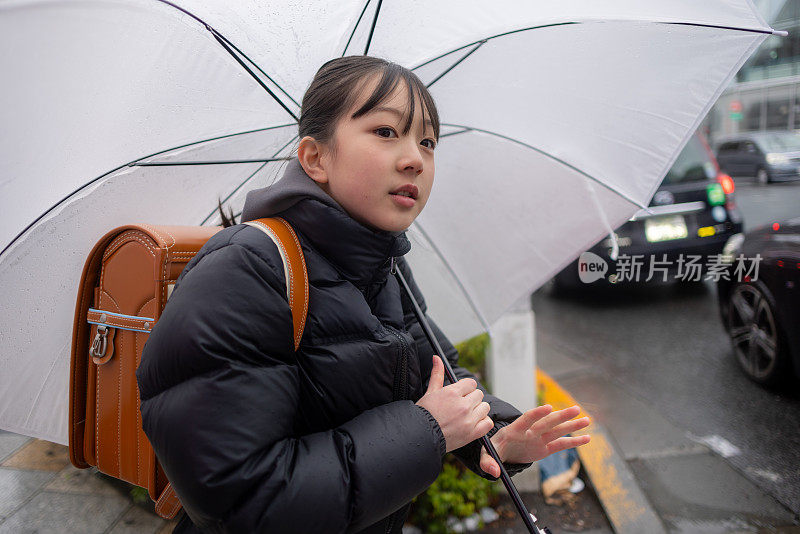 日本一名小学女生在下雨天背着一个“随机”书包