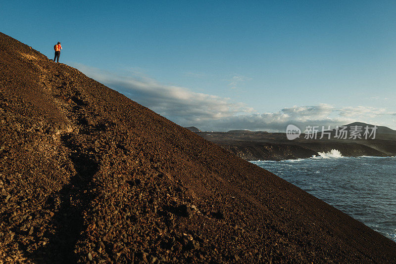 在加那利群岛兰萨罗特岛的火山海岸风景中徒步旅行的妇女