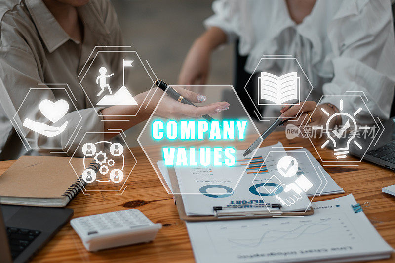 公司价值观概念，业务团队分析办公桌上的收入图表和图形，虚拟屏幕上有公司价值观图标。