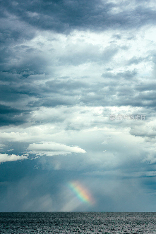 暴风雨云的海景和远处地平线上的彩虹