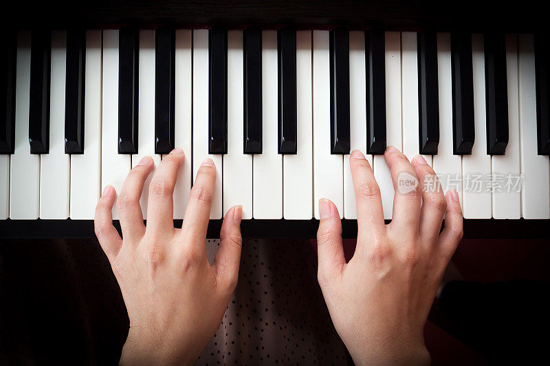 女人的手在弹钢琴。