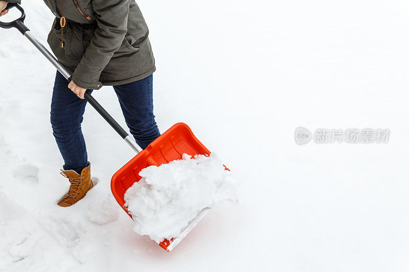 女人用铁锹清理冬天的雪。