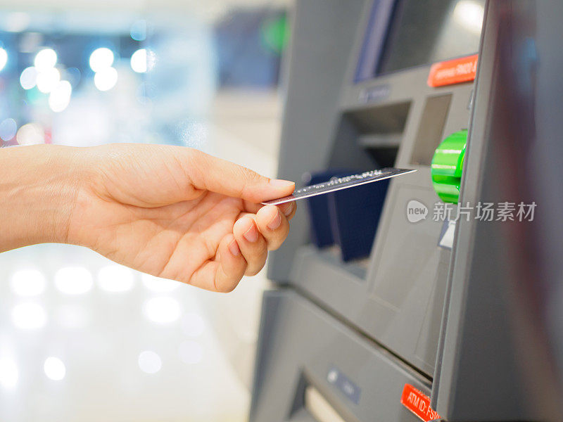 特写的女人的手插入借记卡ATM机。水平。