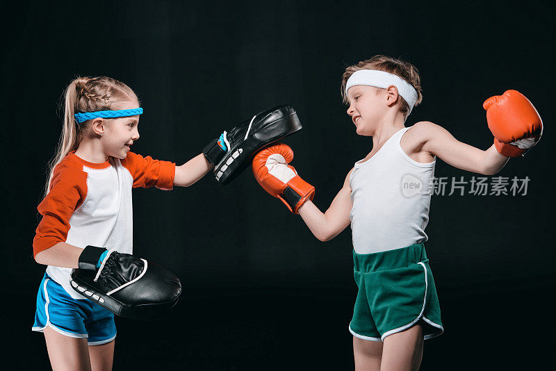 侧视图的男孩和女孩在运动服装孤立的拳击上黑色，活动为儿童概念