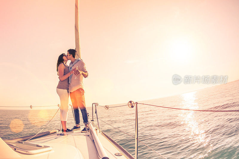 富有的年轻夫妇相爱在帆船上欢呼日落