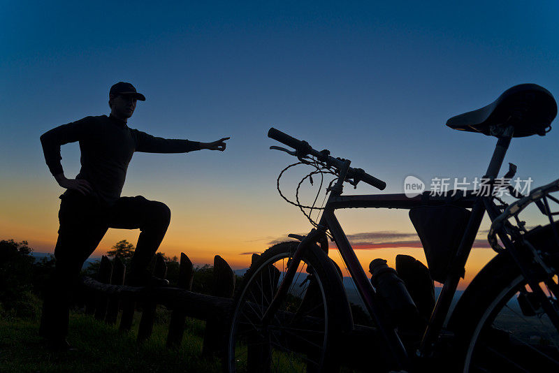 山上骑自行车的人指着夕阳