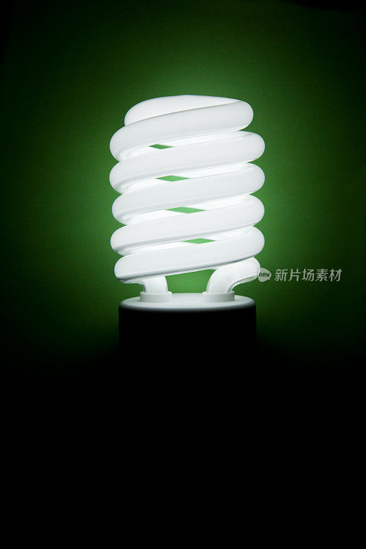 照明紧凑型荧光灯灯泡在一个绿色的背景
