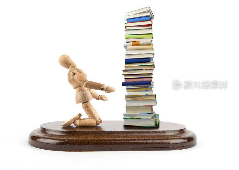 木制人体模型看着一堆书很惊讶