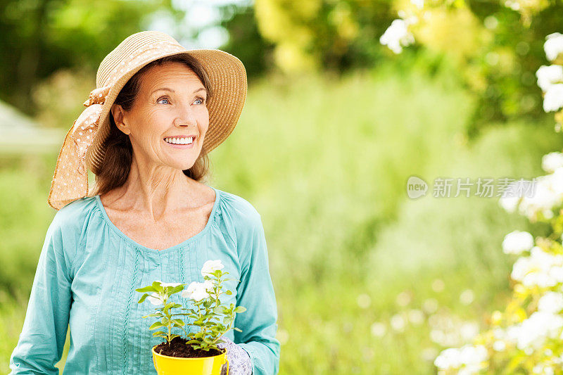 快乐的老女人与盆花植物在花园里