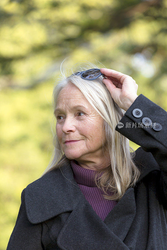 漂亮快乐的资深金发女人戴着太阳镜，户外，复印空间