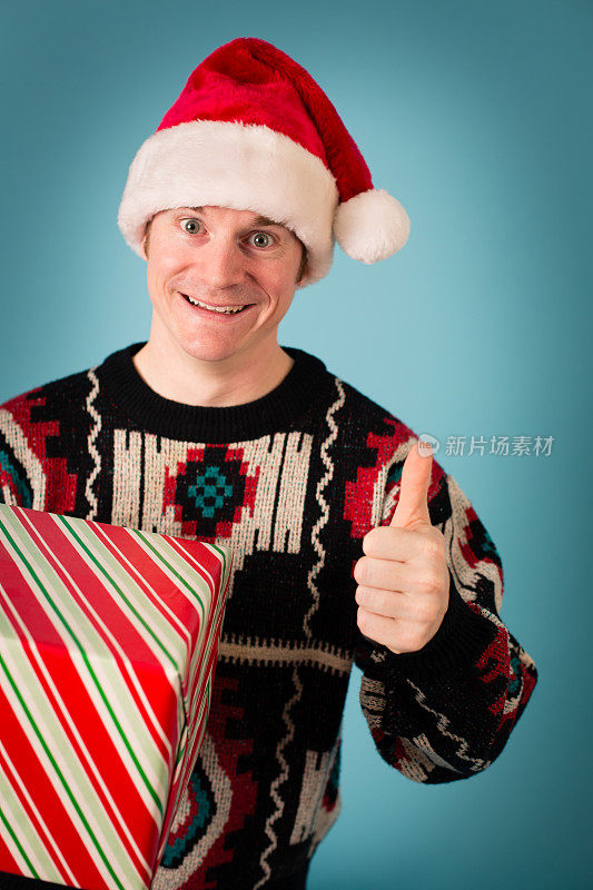 男人，戴着圣诞帽，拿着礼物竖起大拇指