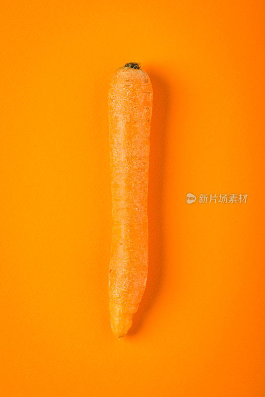 橙色胡萝卜在橙色纸背景，极简主义静物画
