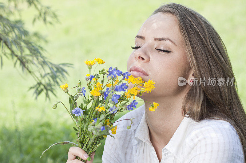 美丽的女孩闻着外面的花