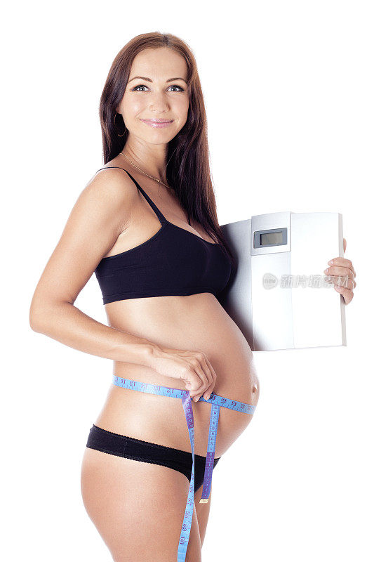拿着磅秤测量腰围的孕妇。