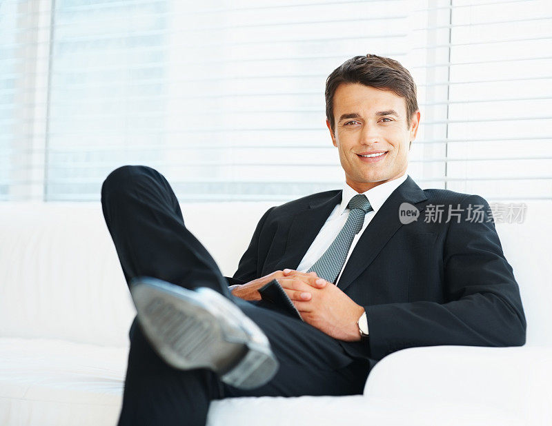 英俊的企业家舒舒服服地坐在沙发上