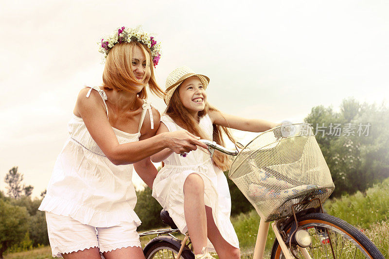 年轻的母亲和她的女儿骑自行车