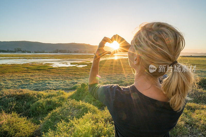 年轻女子把夕阳画成心形