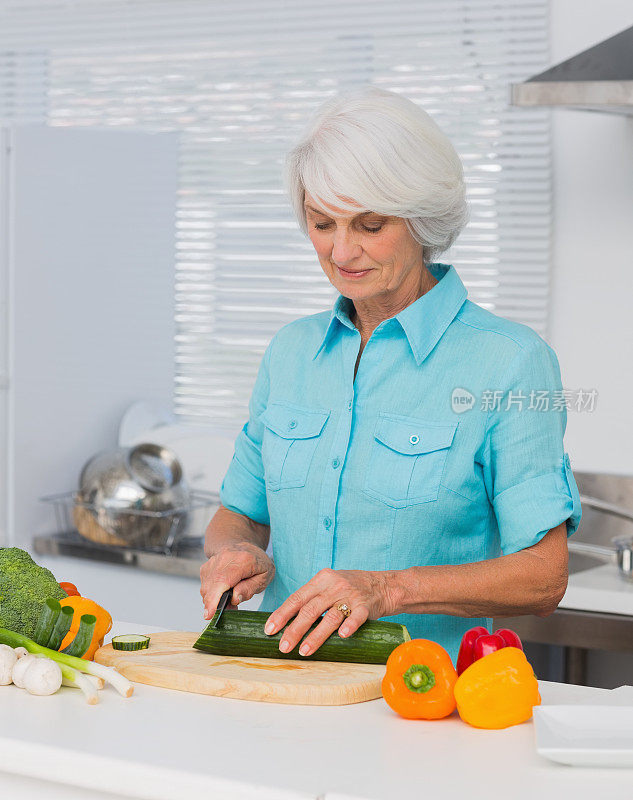 一位年长的女士正在切黄瓜