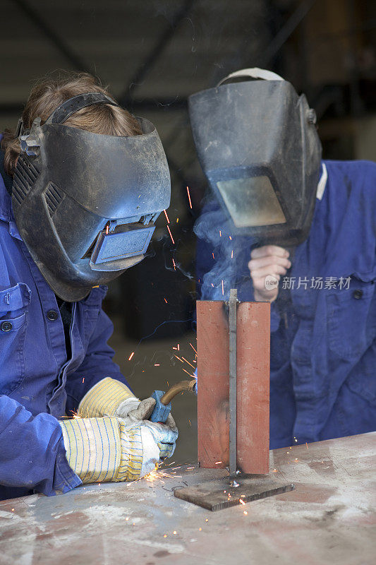 学习对焊机。带焊接面罩的实习生。