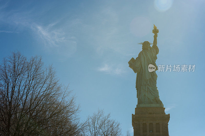 阳光下的纽约自由岛的自由女神像的后视图