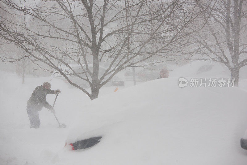 在暴风雪中从车道上铲雪的男人