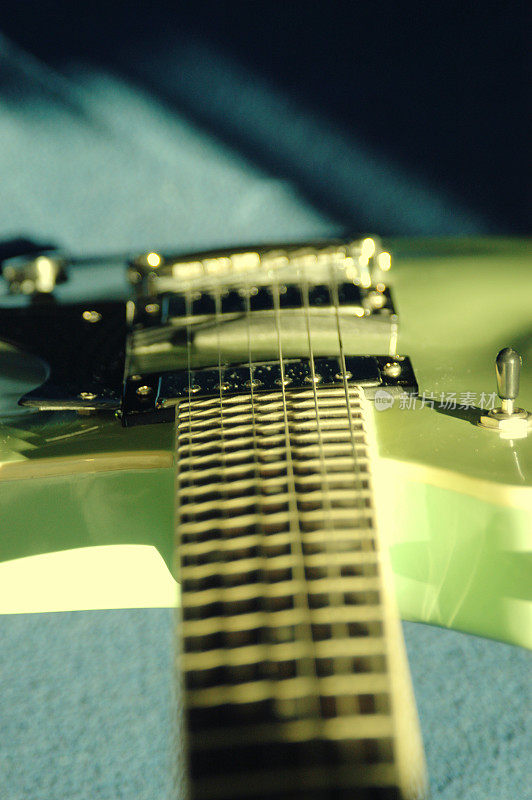 在蓝色的背景下，从脖子往下看，电吉他的主体，自然的光线，长长的阴影。不寻常的角度，向下看电吉他。浅景深，添加instagram滤镜效果。