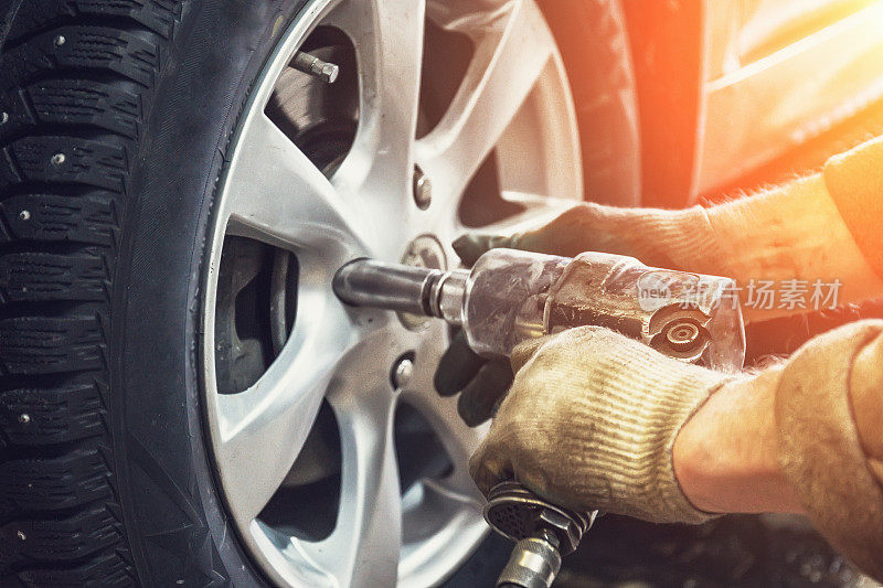 汽车修理工在维修站的车库里用气动扳手做轮胎或车轮的更换