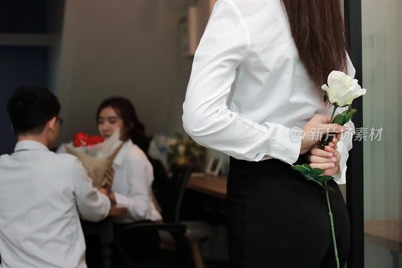 沮丧心碎的亚洲女人拿着白色玫瑰背后的一对情侣情人在情人节的背景。伤害了爱的概念。