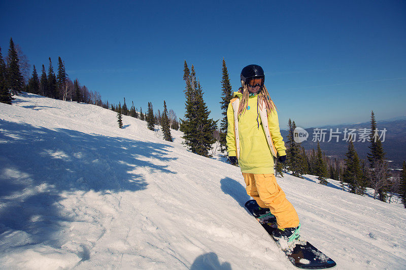 在雪山斜坡上滑行的女性滑雪板运动员