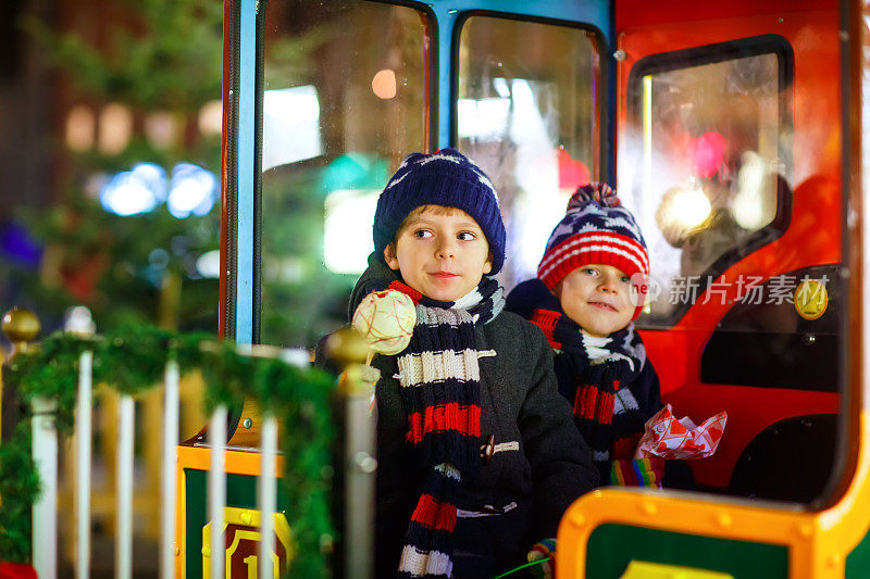 两个小男孩在圣诞市场的旋转木马上