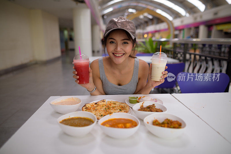 年轻美丽的亚洲女游客在餐厅享受印度美食的肖像