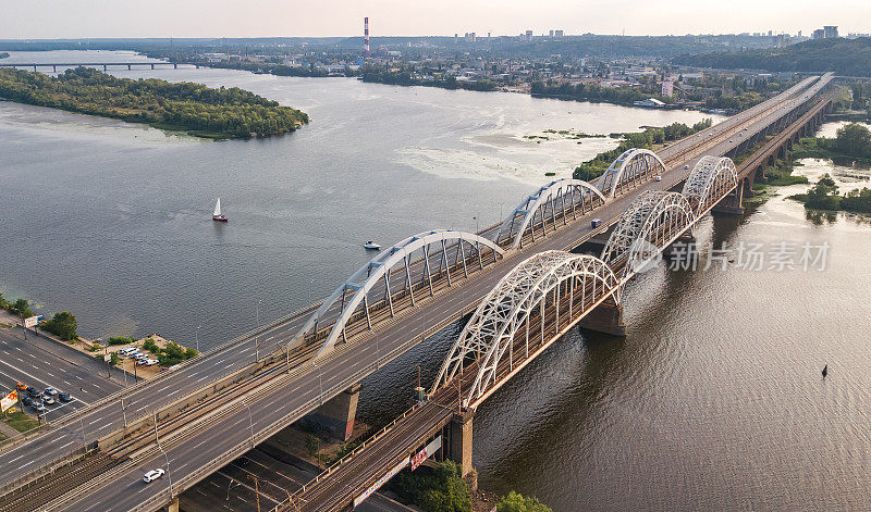 从上空俯瞰横跨第聂伯河的汽车和铁路达尔尼茨基桥，基辅市日落天际线，乌克兰