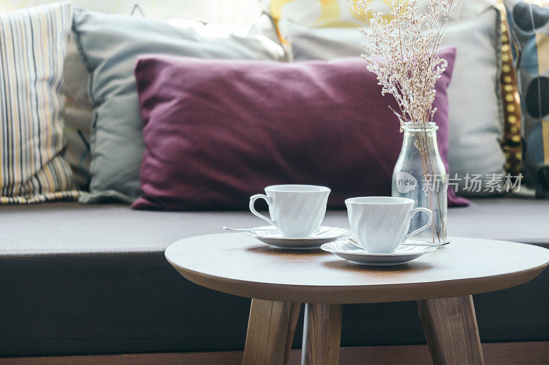 桌上装饰白色咖啡杯、花瓶、沙发枕头