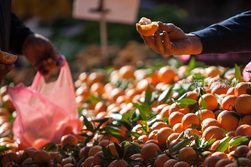 在农贸市场，卖家向买家提供橘子片