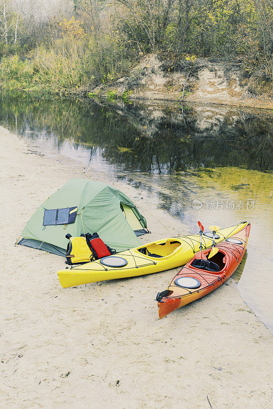 在皮艇漂流。河岸上立着一个帐篷营地。