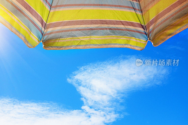 仰望夏日天空的条纹沙滩伞