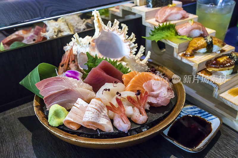 选择性聚焦装饰生鱼片放在碗与冰和海螺壳另一个寿司后面