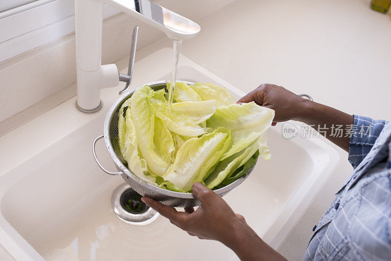 女人的手在厨房里洗生菜。
