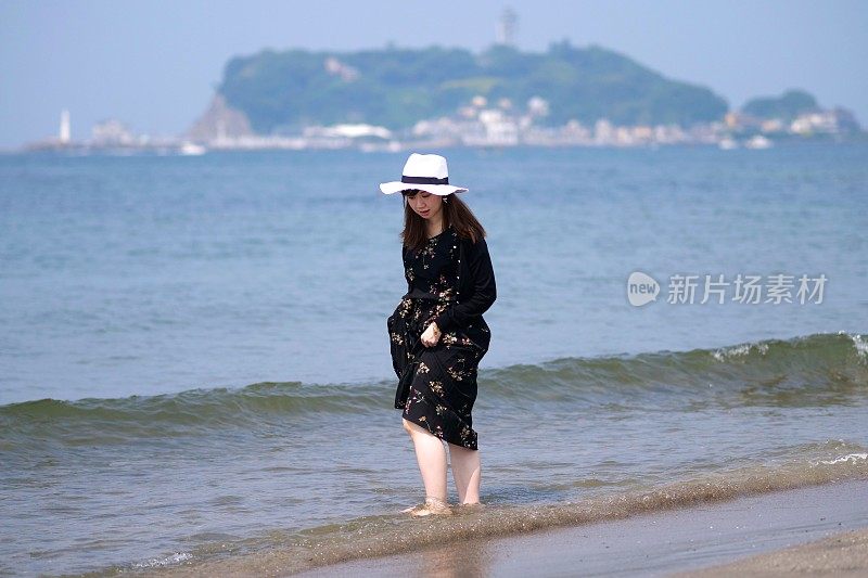 年轻女子走在潮湿的沙滩上