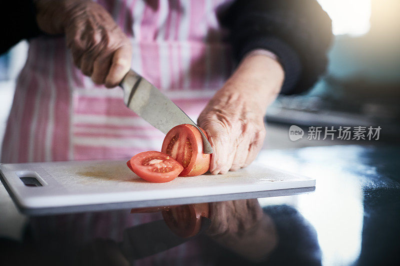 厨房里，女人皱巴巴的手在切西红柿